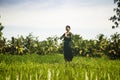 Artistic portrait of young attractive and happy Asian woman outdoors at green rice field landscape dancing and doing spiritual Royalty Free Stock Photo