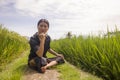 Artistic portrait of young attractive and happy Asian woman outdoors at green rice field landscape dancing and doing yoga Royalty Free Stock Photo