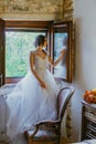Artistic processing Fantasy girl princess in WHITE WEDDING dress stands in medieval CASTLE room looking vintage window Royalty Free Stock Photo