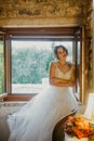 Artistic processing Fantasy girl princess in WHITE WEDDING dress stands in medieval CASTLE room looking vintage window Royalty Free Stock Photo