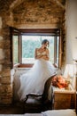 Artistic processing Fantasy girl princess in WHITE WEDDING dress stands in medieval CASTLE room looking vintage window Royalty Free Stock Photo