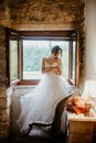 Artistic processing Fantasy girl princess in WHITE WEDDING dress stands in medieval CASTLE room looking vintage window Royalty Free Stock Photo