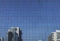 Artistic reflection of various buildings on blue reflective glass curtain wall building facade under clear bright daylight