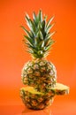 Artistic sliced, standing pineapple on orange background, vertical shot