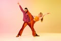 Artistic, talented ,emotional young people, man and woman in stylish clothes dancing disco dance against gradient pink
