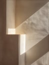 An artistic vertical composition showing sharp geometric shadows and warm morning light on a beige textured wall. Royalty Free Stock Photo
