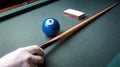 Artistic view of a pool ball with a cue stick and chalk on a felt table