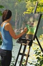 Artistic woman painting acrylic on canvas outside
