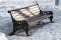 Artistic wooden bench in a city park at a path with footprints in winter