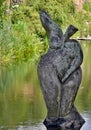 Art in nature - wooden female figure in water in front of green