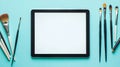 An artistic workspace featuring a tablet, brushes, and paint jars. Royalty Free Stock Photo