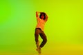 Artistic young female dancer, performing contemporary, hip-hop against gradient green yellow background in neon light Royalty Free Stock Photo