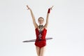 Artistic young gymnast in leotard performing with hula hoop, on white