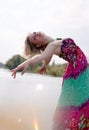 Artistic young lady dancing in long dress by lake
