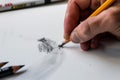 artists hand erasing a mistake on a white paper with a pencil Royalty Free Stock Photo