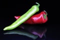 Artsy peppers red green hot strong pepper paprika on isolated black mirror mirrored reflective background.