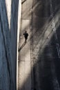 Artsy top view shot of a person walking down a sidewalk under the building shadows