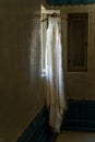 Artsy Wedding Dress Hanging In An Old Room