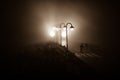 Young couple holding each other hands. Slowly walking under white street lights in night. Dark time. Peaceful atmosphere in mist. Royalty Free Stock Photo