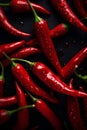 Hot chili peppers depicted in contrast against a dark background. The juicy, red peppers create a visual effect.