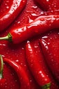 Hot chili peppers depicted in contrast against a dark background. The juicy, red peppers create a visual effect.