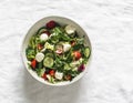 Arugula, cherry tomatoes, cucumbers, mozzarella cheese salad with lemon-mustard dressing on a light background, top view Royalty Free Stock Photo