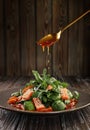 Arugula and mini spinach salad with slices of salmon in sesame seeds, with segments of red oranges and sweet, orange sauce