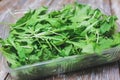 Arugula salad in the plastic box on wooden background. Rucola lettuce healthy food. Vegetarian lifestyle concept. Green fresh Royalty Free Stock Photo