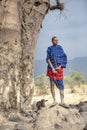 Maasai warrior with a goat under a large baobab tree
