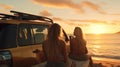 Back of two surfer girls on the beach at sunset, next to four wheel drive