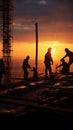 As night falls, the construction site silhouette reveals crane and laborers