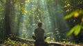 As sunlight filters through the foliage above a person sits on a fallen log back hunched as they contemplate the secrets