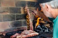 Asado. Argentinian mature man making a barbecue in the grill of his house.