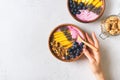 Asai bowl granola oatmeal with mango, blueberry and chia seeds in wooden plate with female hands on white background