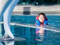 Asain boy in a swimming pool wearing a life vest