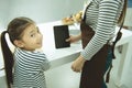Asain girl look at camera while cooking flour on withe table with mom hold tablet Royalty Free Stock Photo