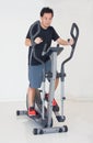 Asain Man Doing Exercises On Elliptical Cross Trainer.