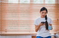 Asain woman listening music with mobile and drink coffee sitting on counter in kitchen at home.leisure activity