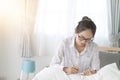 Asain woman writing on bed