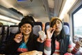 Asain women mother and daughter eating snack and listen music on mobile phone on train