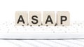ASAP -word wooden block on keyboard background witn chart