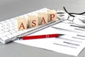 ASAP written on a wooden cube on the keyboard with chart on grey background