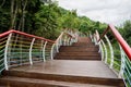 Ascending hillside planked walkway with colorful steel railing after summer rain