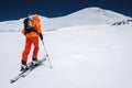 Ascent of a skier with a backpack in a mask and sunglasses on skis with poles to go uphill for freeride and backcountry