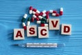 ASCVD - acronym on wooden cubes on a blue background with tablets and thermometer