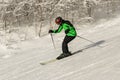 ASHA, RUSSIA - 27 april 2011: male skier moves down the slope against trees in the snow, wearing black and green ski suit mask and Royalty Free Stock Photo