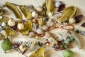 Fall background of yellowed leaves with coral beads,nuts,dried rose buds and stones spread on light plywood