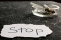 Ashtray with burnt cigarettes and word Stop written on paper on black textured table, closeup. No smoking concept Royalty Free Stock Photo