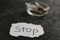 Ashtray with burnt cigarettes and word Stop written on paper on black textured table, closeup. No smoking concept Royalty Free Stock Photo