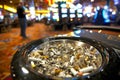 ashtray overflowing with stubs on casino floor with gambler